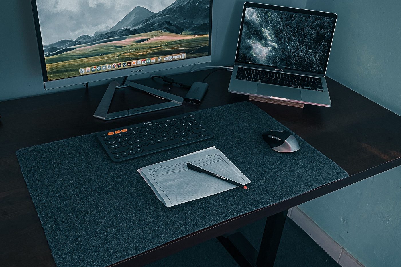 Dark felt desk mat with a keyboard and mouse on a wooden desk (representative photo, not the Logitech product).